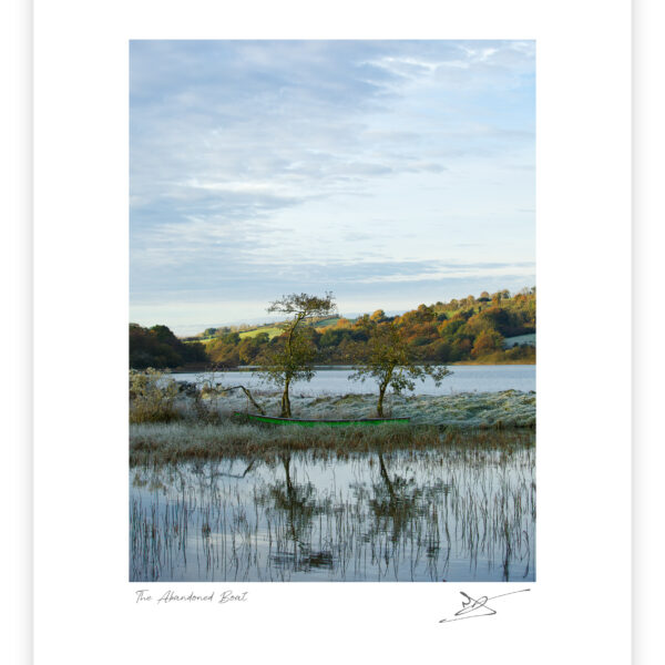 Rowboat beside a still lake with two trees and autumn hills reflected in the water in County Cavan.