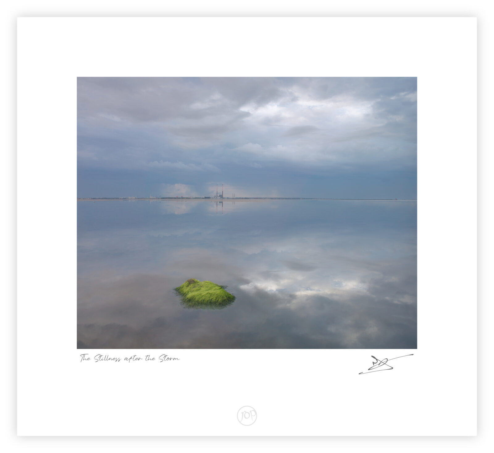 Moss-covered rock reflected in still water at Blackrock, Dublin Bay, with Poolbeg chimneys on the horizon.