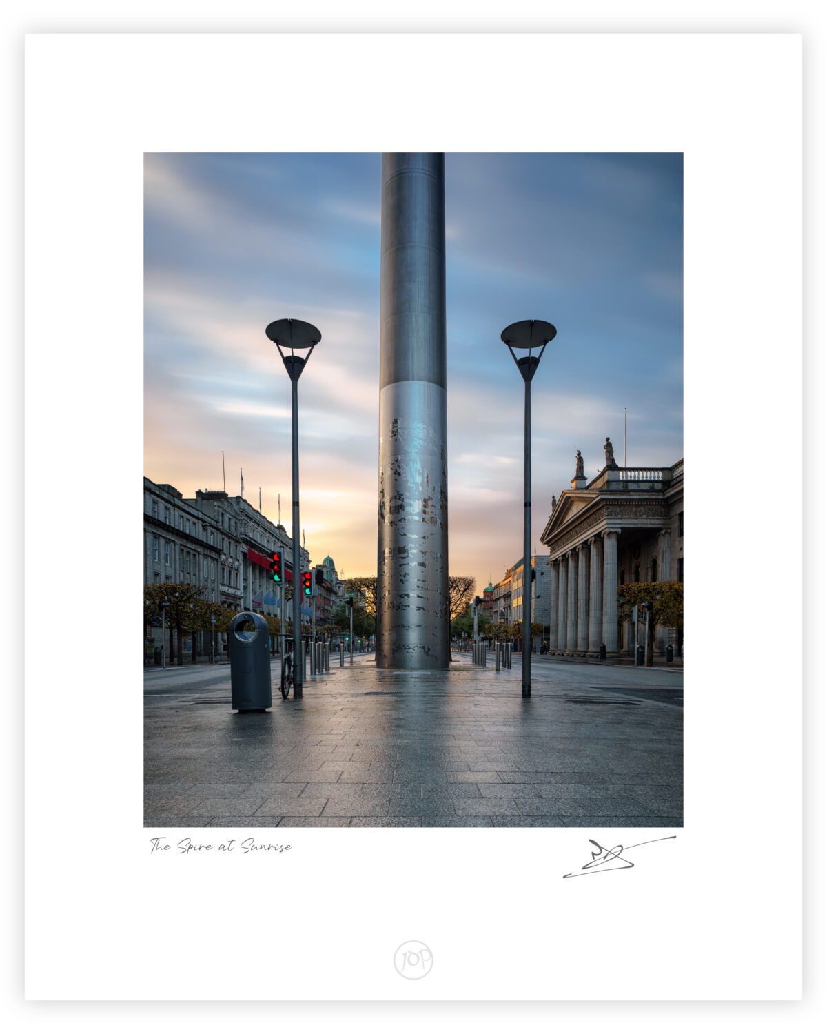 The Spire of Dublin at sunrise on O’Connell Street, viewed straight on with soft morning light and empty streets.