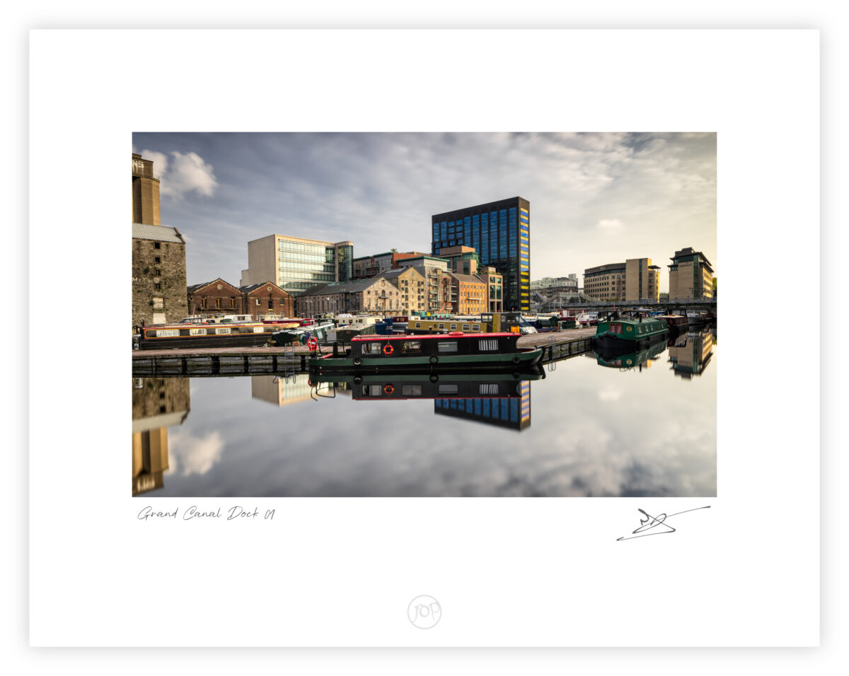 Grand Canal Dock in Dublin with moored barges and reflected city buildings in calm water, Ireland, colour photograph.