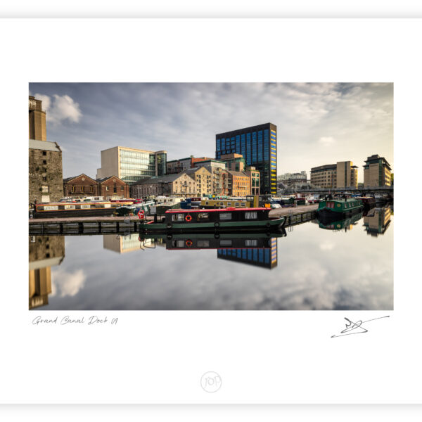 Grand Canal Dock in Dublin with moored barges and reflected city buildings in calm water, Ireland, colour photograph.