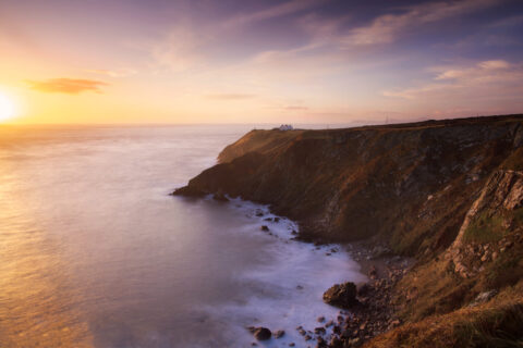 Sunrise light on the cliffs and lighthouse at Howth Head overlooking the Irish Sea, Dublin.