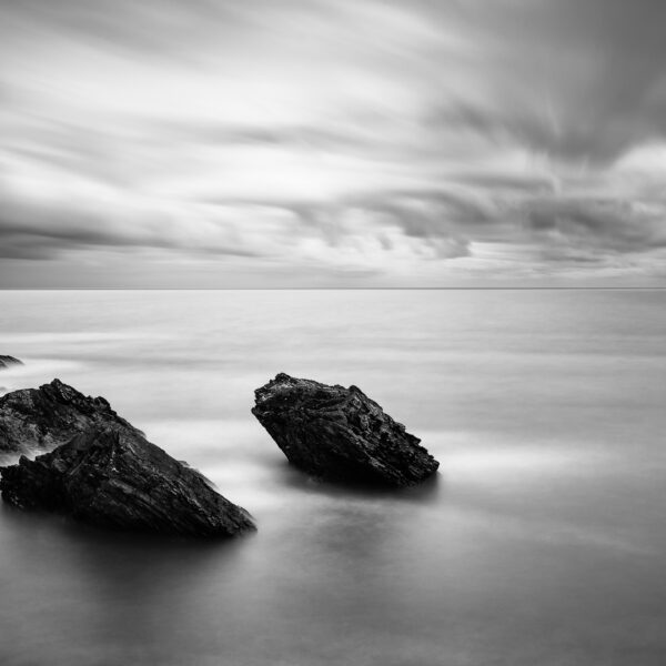Cargo ship leaving Wicklow Port with rocks in the foreground and clouds over the Irish Sea.