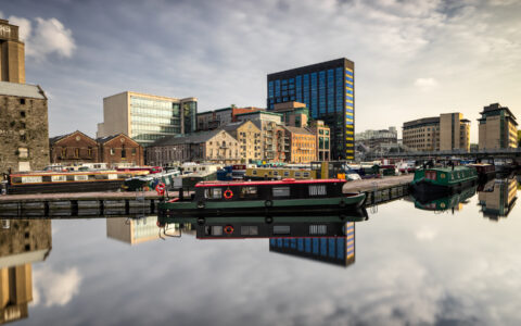 Grand Canal Dock in Dublin with moored barges and reflected city buildings in calm water, Ireland, colour photograph.