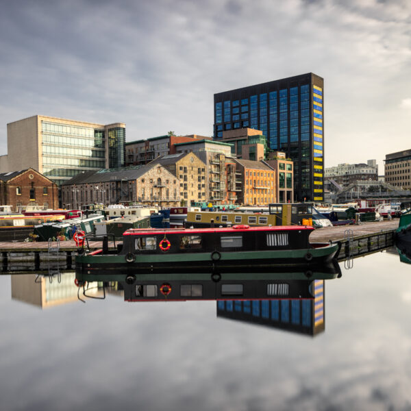Grand Canal Dock in Dublin with moored barges and reflected city buildings in calm water, Ireland, colour photograph.