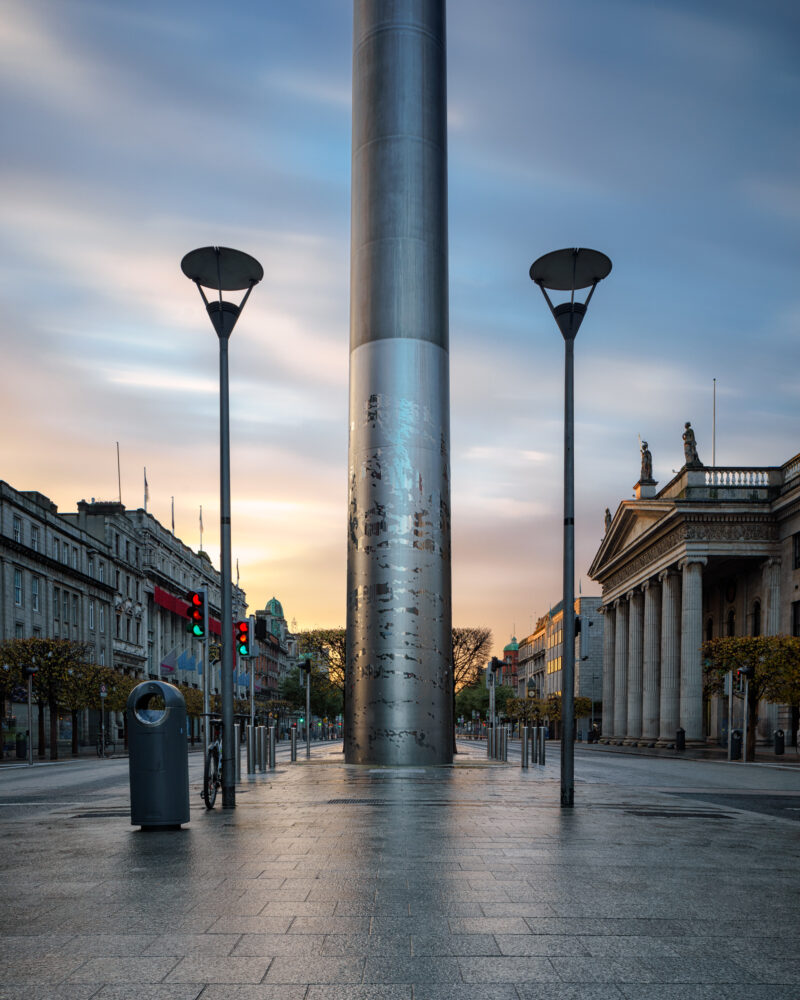 The Spire of Dublin at sunrise on O’Connell Street, viewed straight on with soft morning light and empty streets.