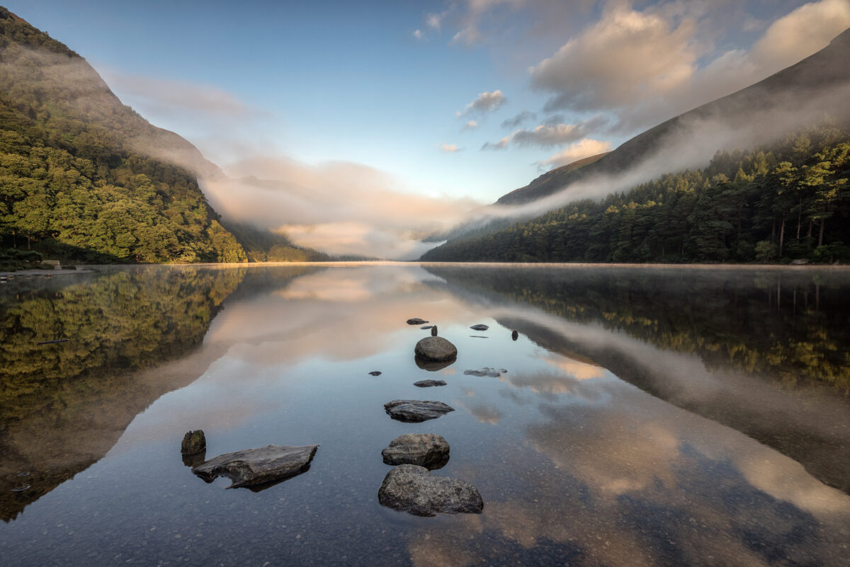 Sunrise at Glendalough's Upper Lake #1 Mist rising over Upper Lake in Glendalough with rocks reflected in still water in County Wicklow.