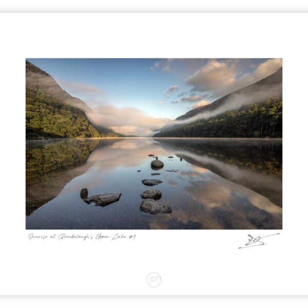 Mist rising over Upper Lake in Glendalough with rocks reflected in still water in County Wicklow.