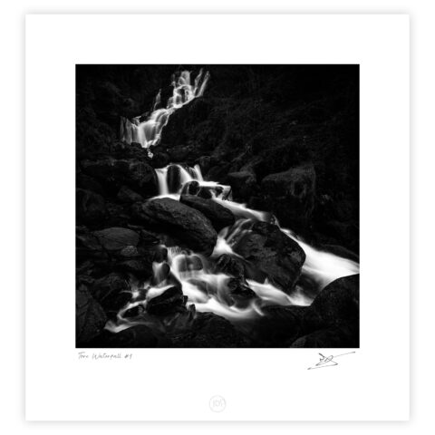 Black and white photograph of Torc Waterfall flowing over rocks in Killarney National Park, Ireland.