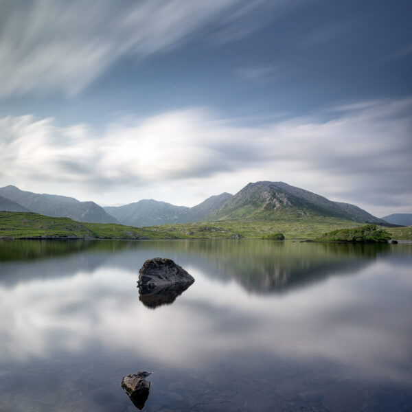 Mount Bencorr and the Twelve Pins reflected in calm water at Derryclare Lough in Connemara, Galway, Ireland, colour photograph.