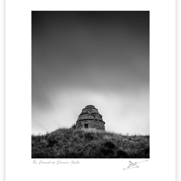 Stone dovecot of Dunure Castle on a grassy hill above the beach at Ayr, Scotland, black and white photograph.
