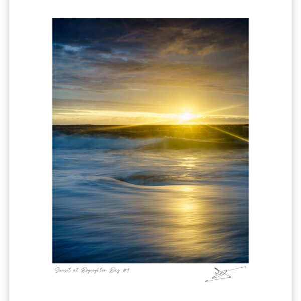 Sunset light breaking beneath clouds over the Atlantic at Murder Hole Beach on the Rosguill Peninsula in Donegal, Ireland, colour photograph.