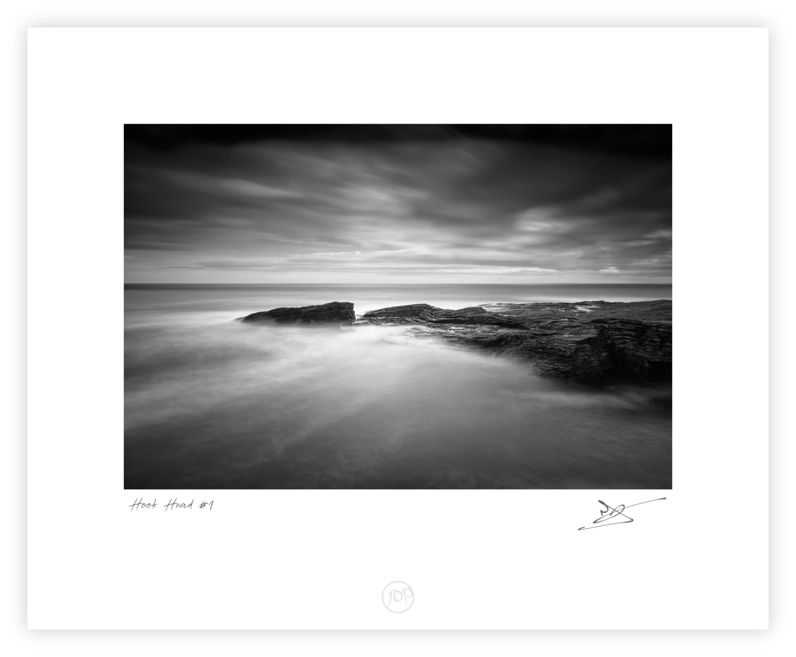 Black and white long-exposure photograph of waves flowing over layered rock shelves at Hook Head on the Wexford coast, Ireland.