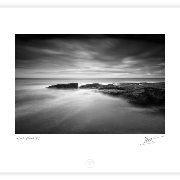 Black and white long-exposure photograph of waves flowing over layered rock shelves at Hook Head on the Wexford coast, Ireland.