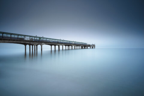 Boscombe Pier extending into a foggy sea at dawn in Bournemouth, England, colour photograph.