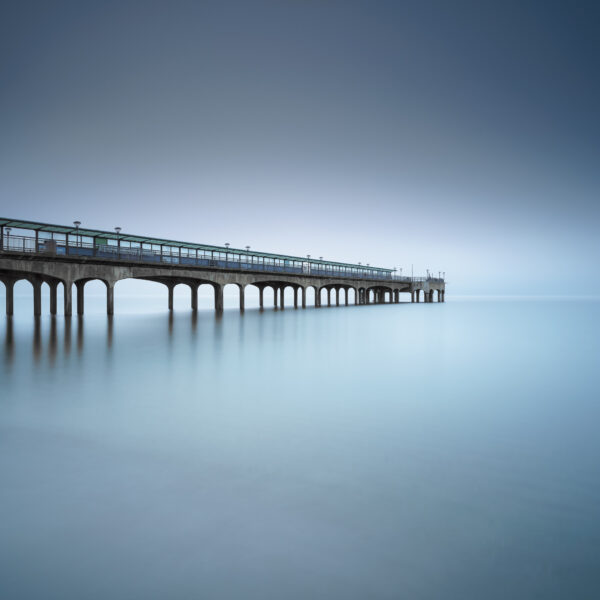 Boscombe Pier extending into a foggy sea at dawn in Bournemouth, England, colour photograph.