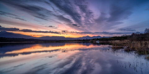 Sunrise over Lough Caragh with reflected clouds and mountains in County Kerry, Ireland.