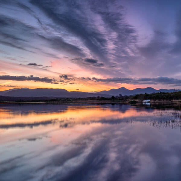 Sunrise over Lough Caragh with reflected clouds and mountains in County Kerry, Ireland.