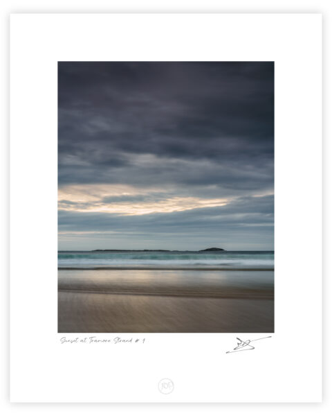Tramore Strand near Downings in Donegal at sunset with soft waves, pastel sky, and distant islands, Ireland, colour photograph.