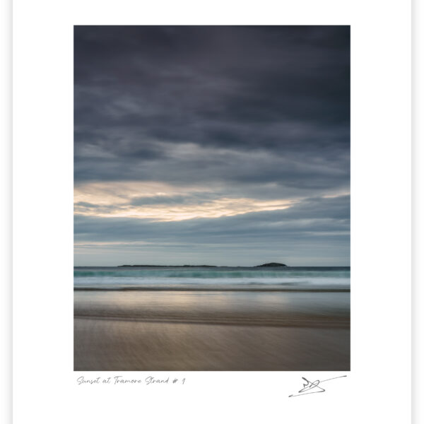 Tramore Strand near Downings in Donegal at sunset with soft waves, pastel sky, and distant islands, Ireland, colour photograph.