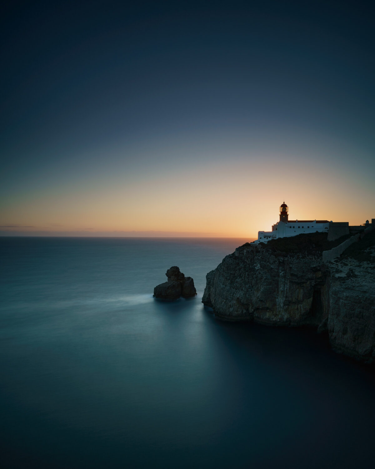 Sunset at the Lighthouse of Cabo de São Vicente #1 Lighthouse of Cabo de São Vicente on coastal cliffs at sunset in Sagres, Algarve, colour photograph.