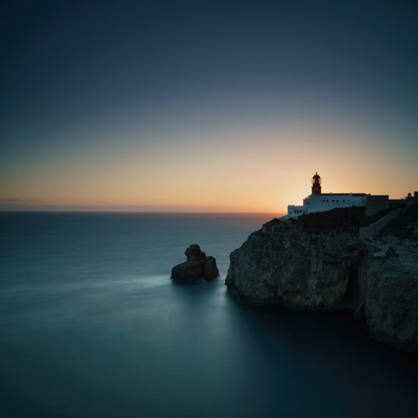 Lighthouse of Cabo de São Vicente on coastal cliffs at sunset in Sagres, Algarve, colour photograph.