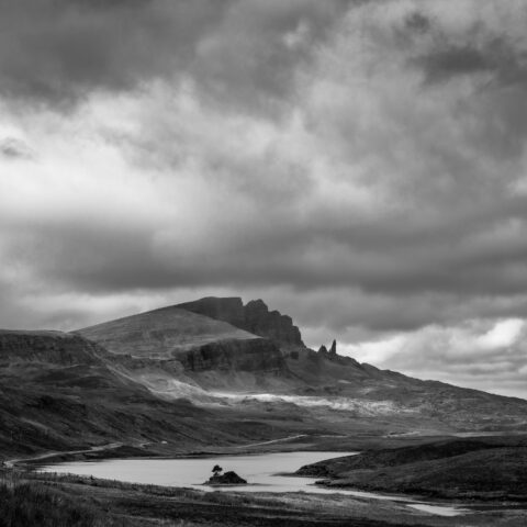 Old Man of Storr rock pinnacle beneath dark clouds on the Isle of Skye, Scotland, black and white photograph.
