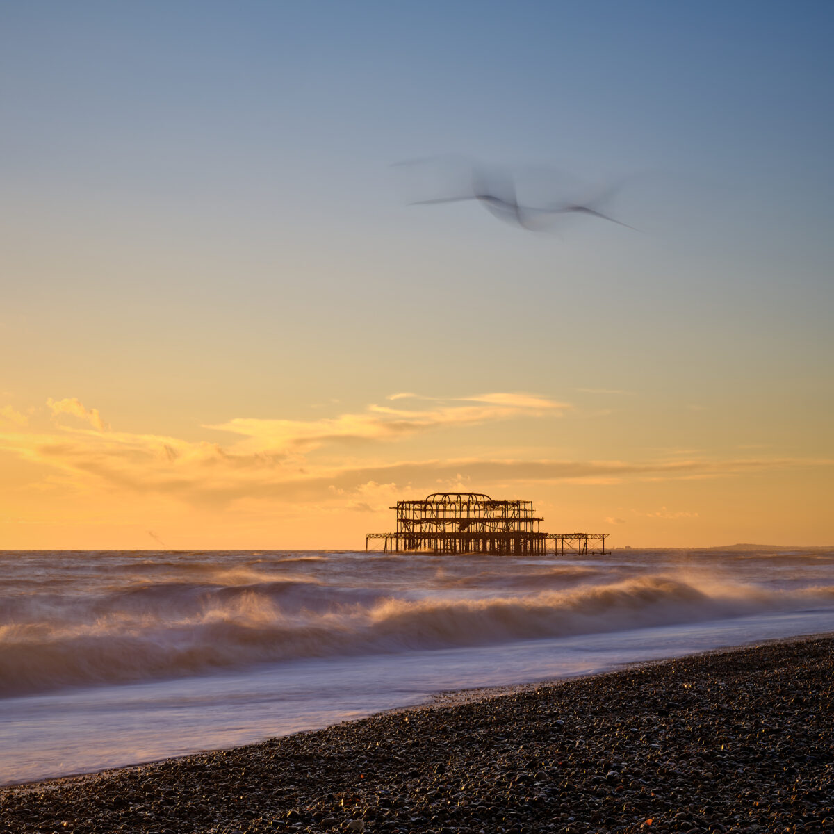 Sunset at Brighton's West Pier #1 Waves breaking at sunset with the ruined West Pier offshore on Brighton beach, England, colour photograph.