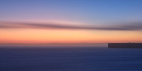 Sunset light behind Cabo de São Vicente Lighthouse in Sagres on the Algarve coast, colour photograph.