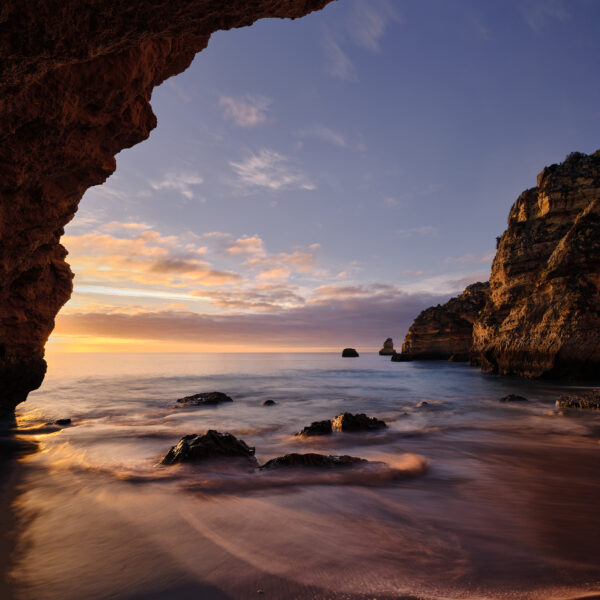 Sunrise light illuminating a sheltered cove at Praia da Dona Ana on the Algarve coast, colour photograph.