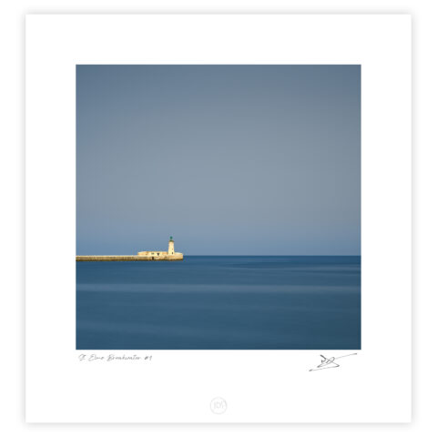 St Elmo Lighthouse on the breakwater viewed from Valletta with calm sea and clear sky, Malta, colour photograph.