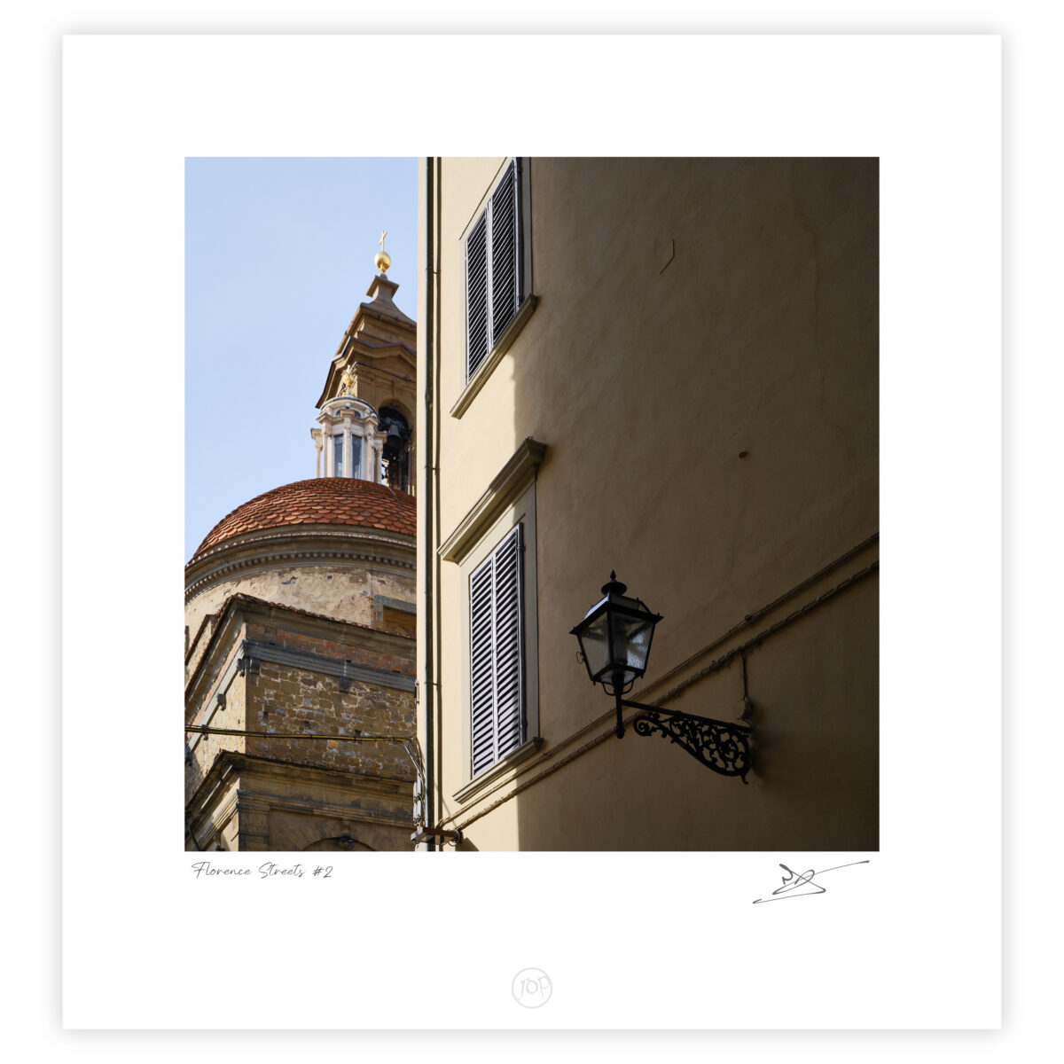 Sunlit Florentine street with sharp shadows framing the steeple of the Basilica di San Lorenzo, Florence, Italy, colour photograph.