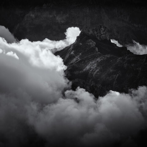 Pico do Areeiro mountain ridge emerging through cloud inversion at sunset, black and white photograph.