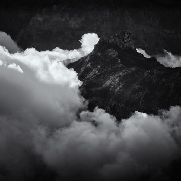 Pico do Areeiro mountain ridge emerging through cloud inversion at sunset, black and white photograph.