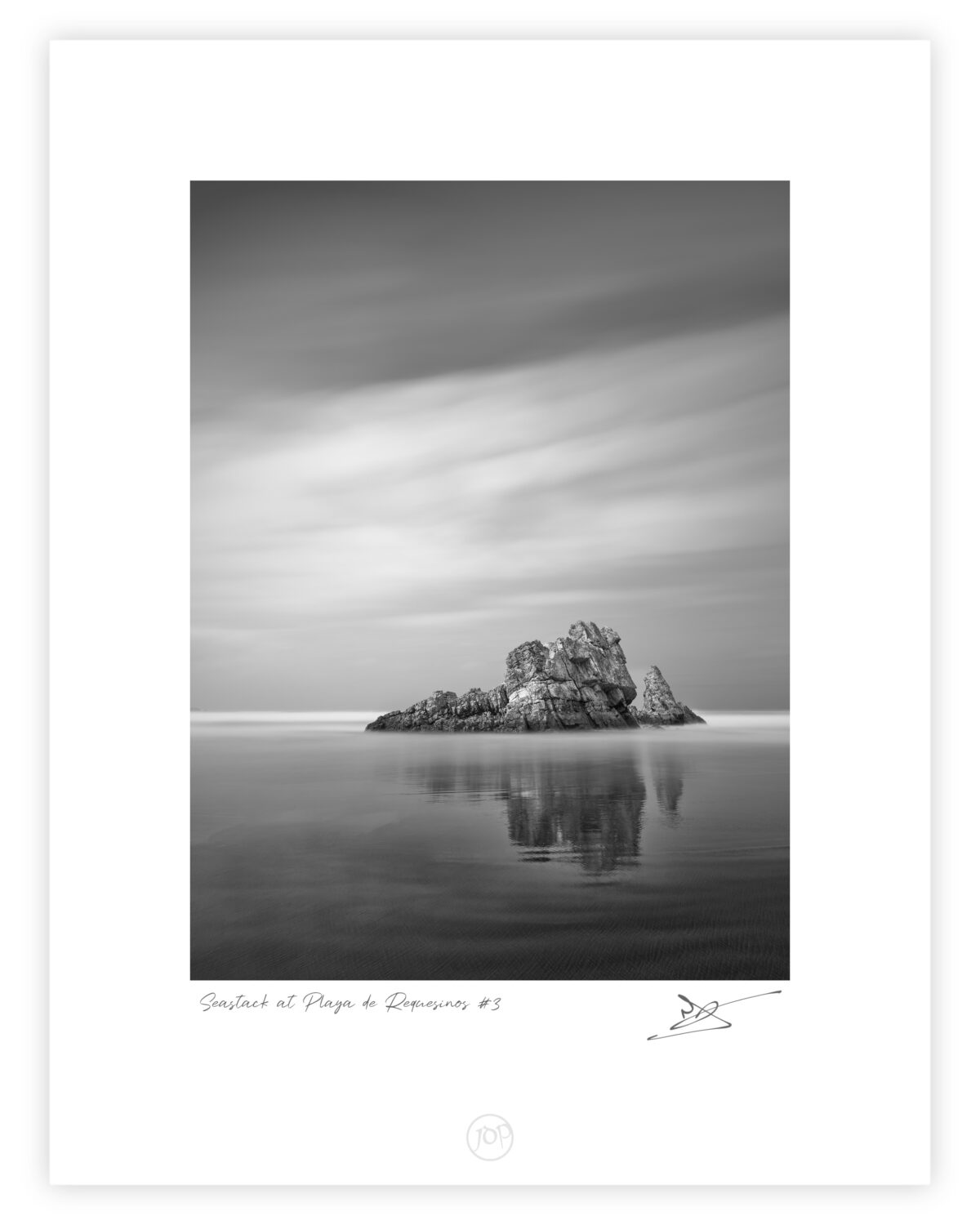 Seastack at Playa de Requesinos #3 Matte Black and white long exposure photograph of a low, jagged sea stack emerging from smooth tidal water with a soft sky above, Playa de Requesinos, Asturias, Spain.